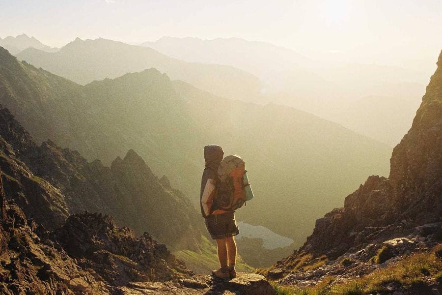 A hiker pausing at a mountain overlook in the morning light