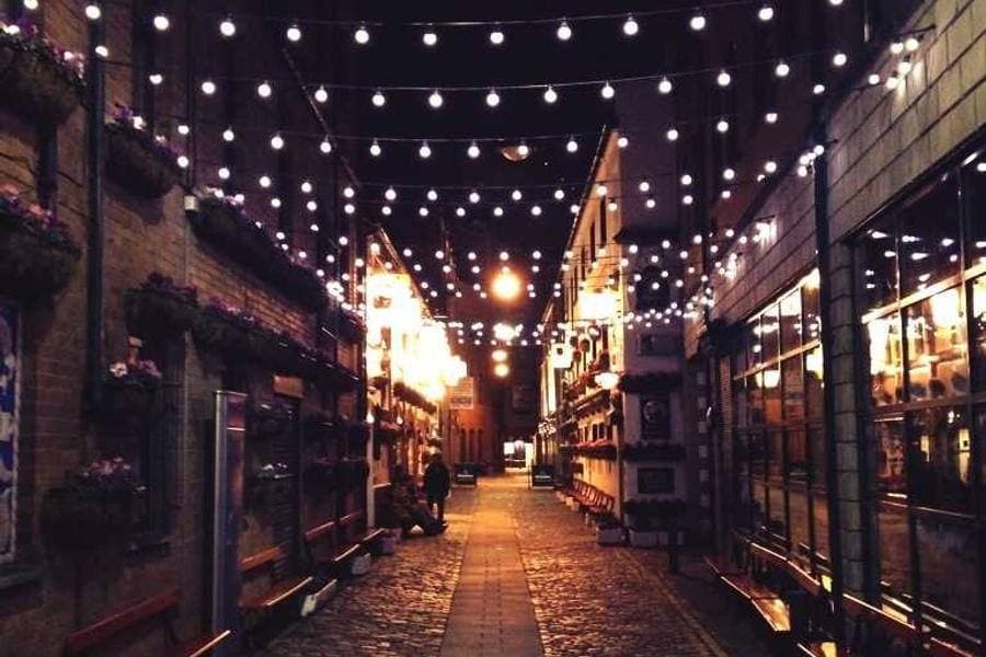 A cobbled lane lit with string lights in the evening